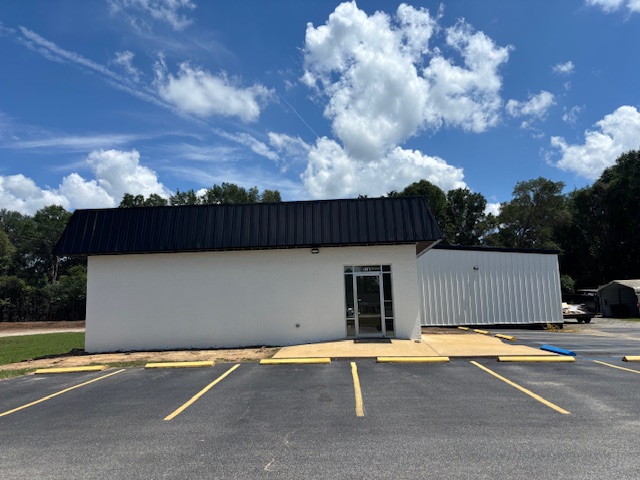 White commercial building with a black metal roof